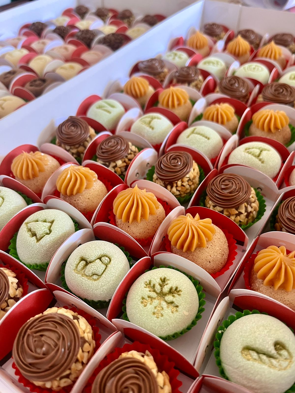 Brigadeiros sortidos com temas de fim de ano em forminhas vermelhas.