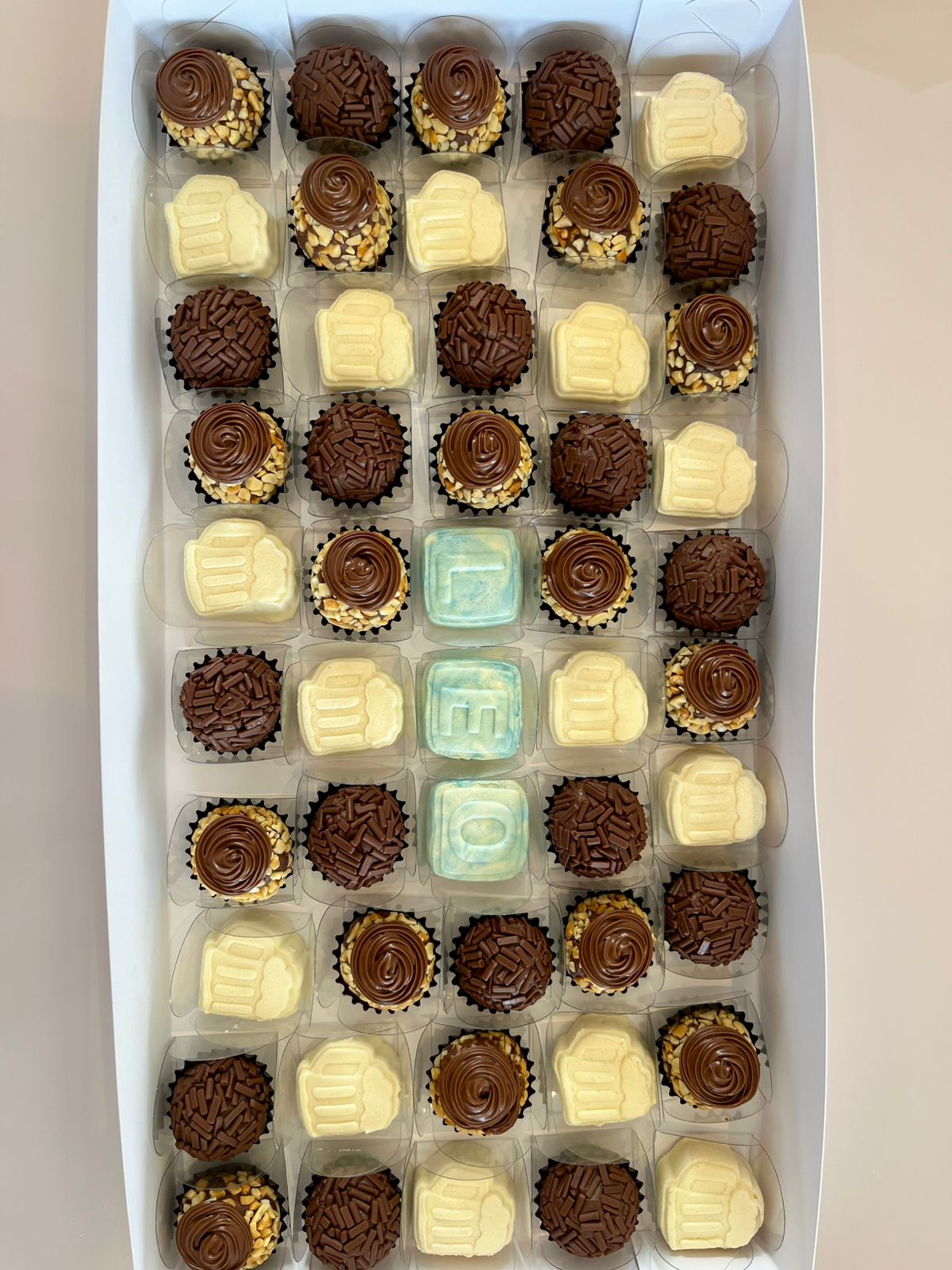 Caixa com brigadeiros sortidos organizada em grade.