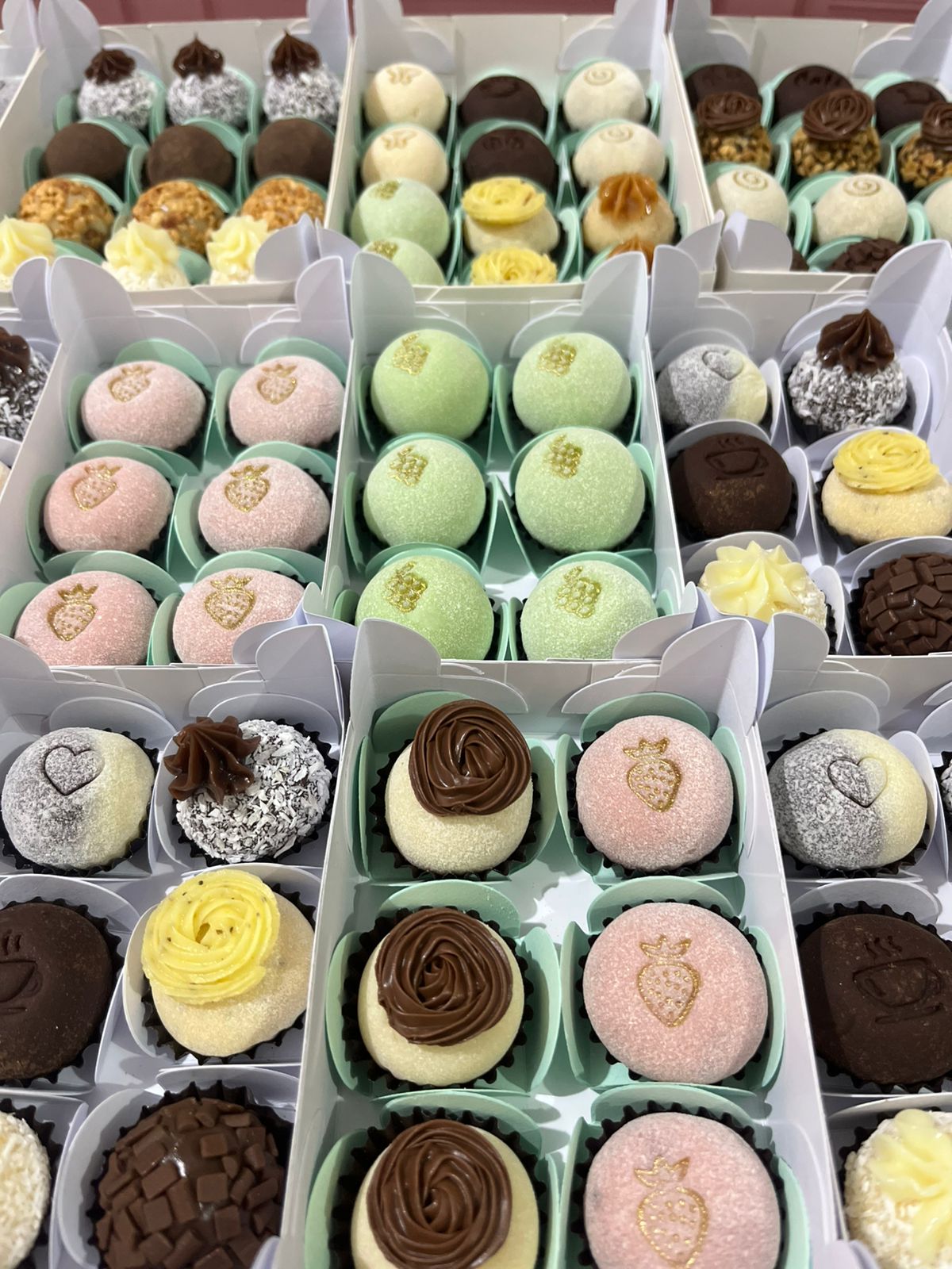 Seleção de caixas com brigadeiros sortidos em tons pastel.